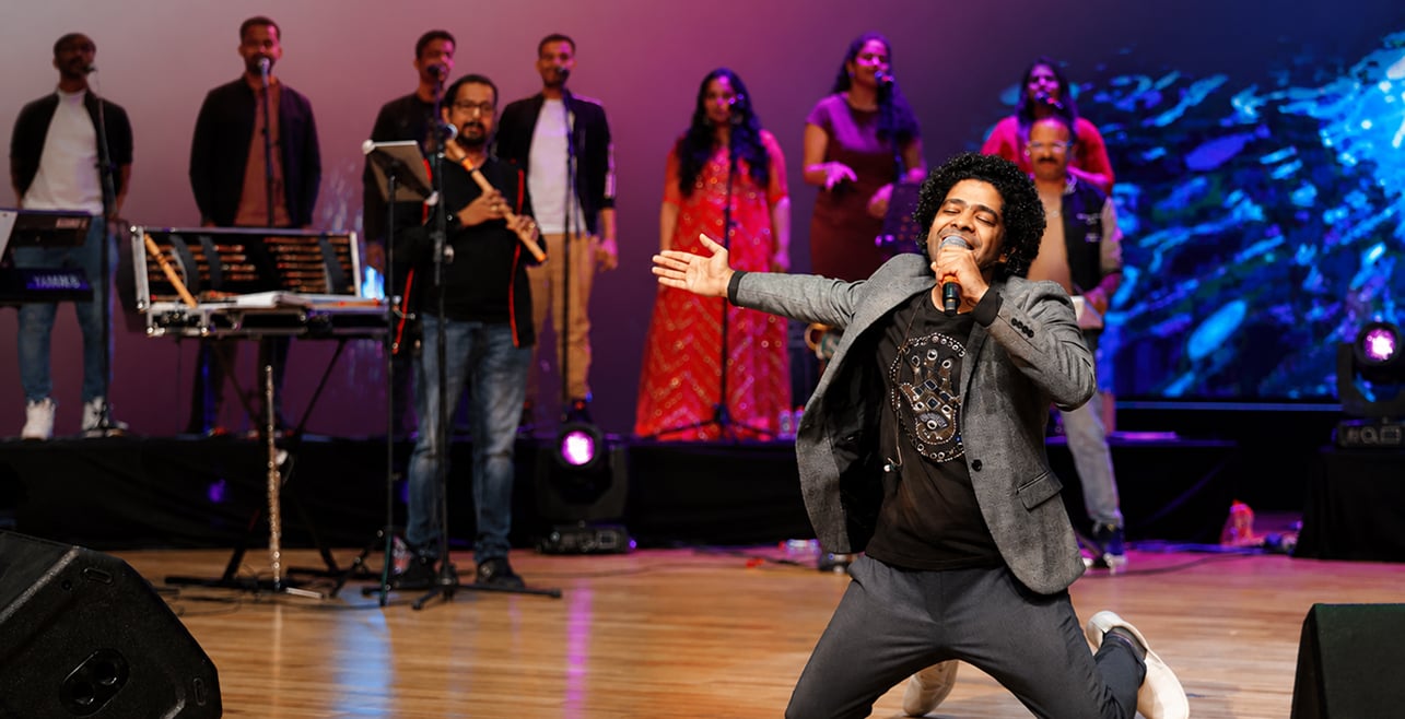 A vocalist performing centre stage at Melody Dreamz, the live band behind him